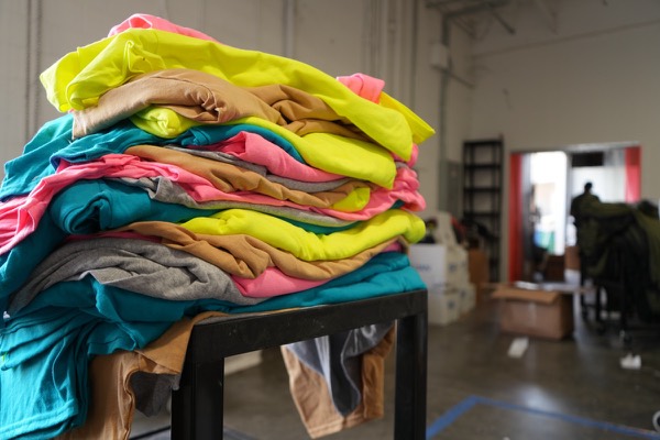 Tall stack of colorful finished custom tees